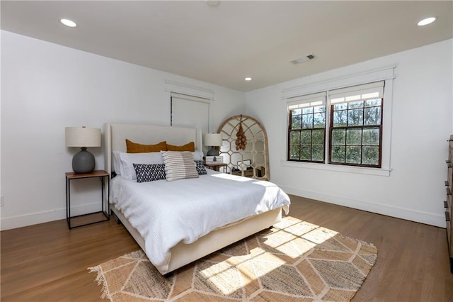 bedroom with baseboards, visible vents, wood finished floors, and recessed lighting