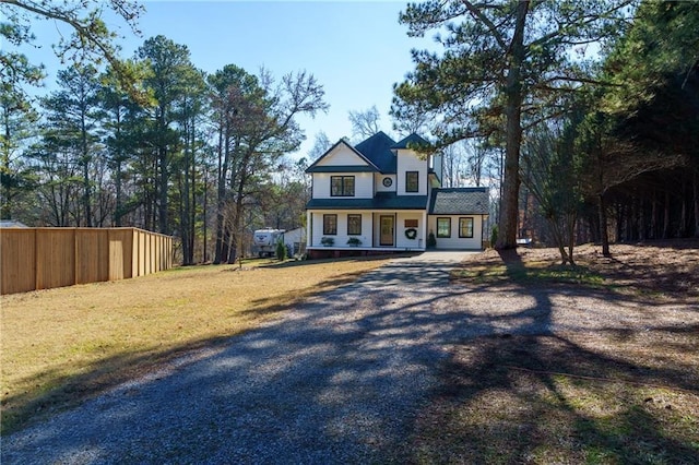 view of front of house featuring driveway, a front lawn, and fence