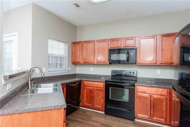 2384 Coach Way, Jonesboro, GA 30236 - kitchen with a sink, brown cabinets, dark wood-type flooring, black appliances, and visible vents