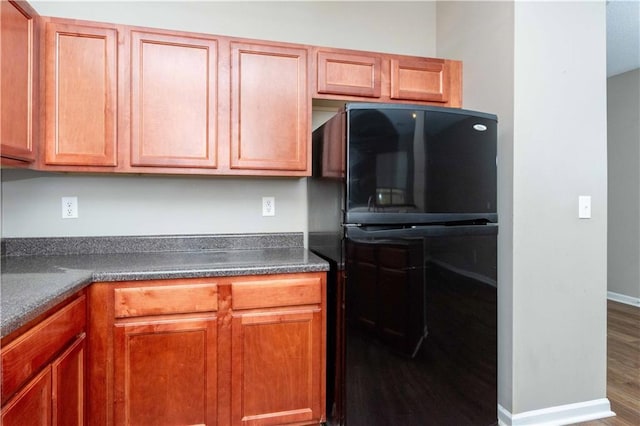2384 Coach Way, Jonesboro, GA 30236 - kitchen with wood finished floors, freestanding refrigerator, brown cabinetry, dark countertops, and baseboards