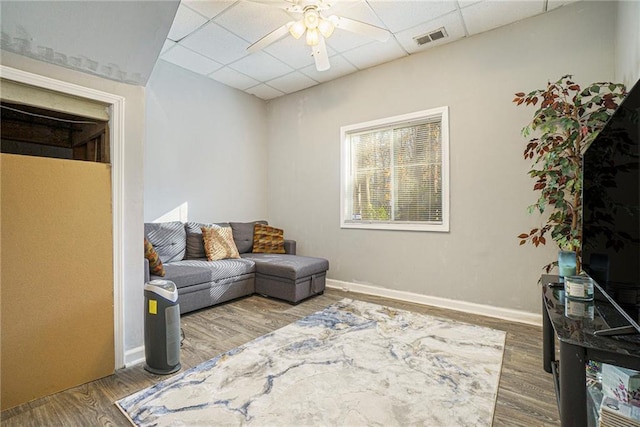 living room with hardwood / wood-style flooring, a paneled ceiling, and ceiling fan