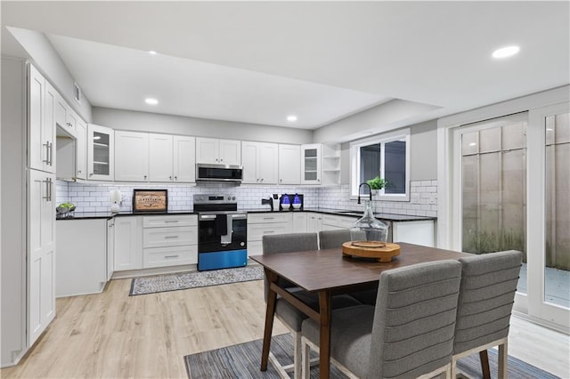 kitchen featuring white cabinetry, sink, light hardwood / wood-style flooring, backsplash, and appliances with stainless steel finishes