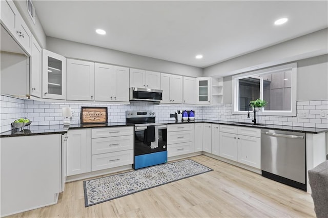 kitchen featuring appliances with stainless steel finishes, tasteful backsplash, sink, light hardwood / wood-style flooring, and white cabinets