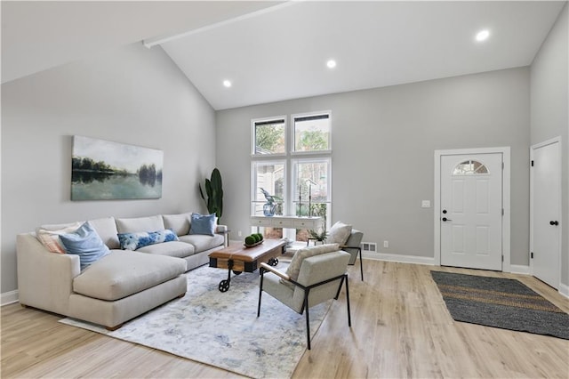 living room with light wood-type flooring and high vaulted ceiling