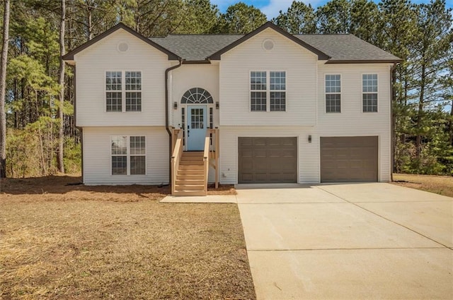 split foyer home with a garage, driveway, and a shingled roof