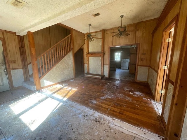 interior space featuring ceiling fan, a textured ceiling, and wooden walls