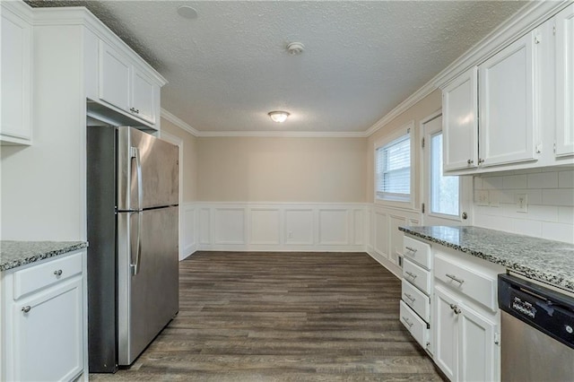 kitchen with a wainscoted wall, dark wood-style floors, stainless steel appliances, white cabinets, and light stone countertops