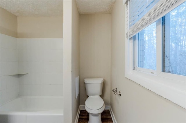 full bathroom with a textured ceiling, baseboards, walk in shower, toilet, and a bathtub