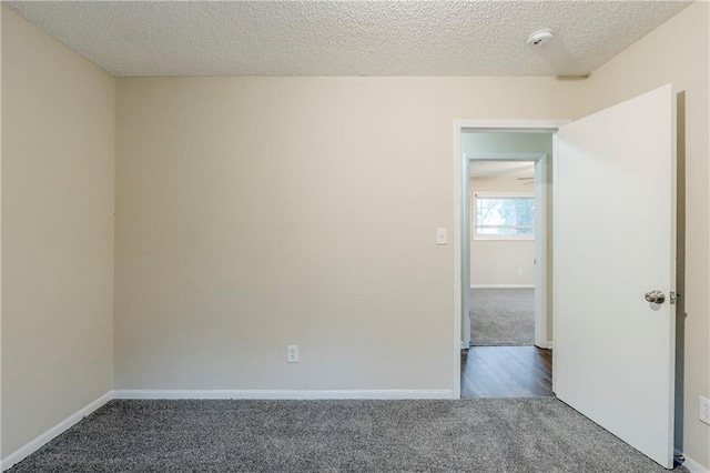 empty room with carpet flooring, a textured ceiling, and baseboards