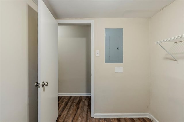 clothes washing area with electric panel, wood finished floors, and baseboards