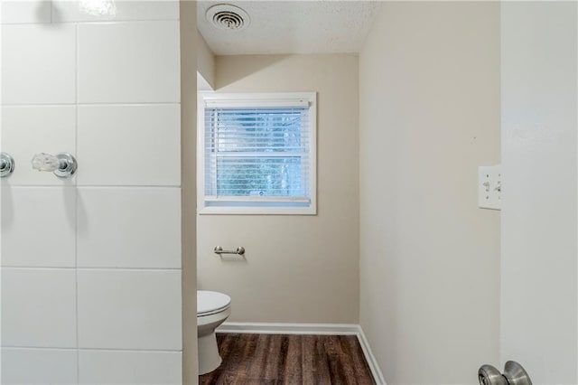 bathroom with wood finished floors, visible vents, baseboards, a textured ceiling, and toilet