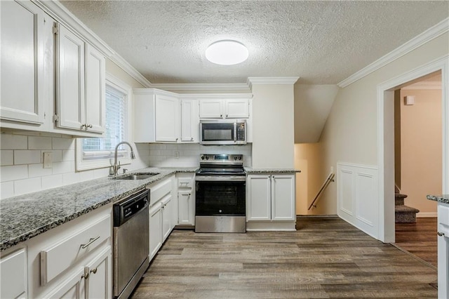 kitchen with light stone counters, wood finished floors, a sink, appliances with stainless steel finishes, and crown molding