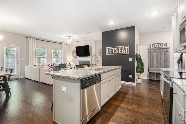 7086 Gladstone Cir, Lithonia, GA 30038 - kitchen with appliances with stainless steel finishes, open floor plan, a ceiling fan, white cabinetry, and a warm lit fireplace