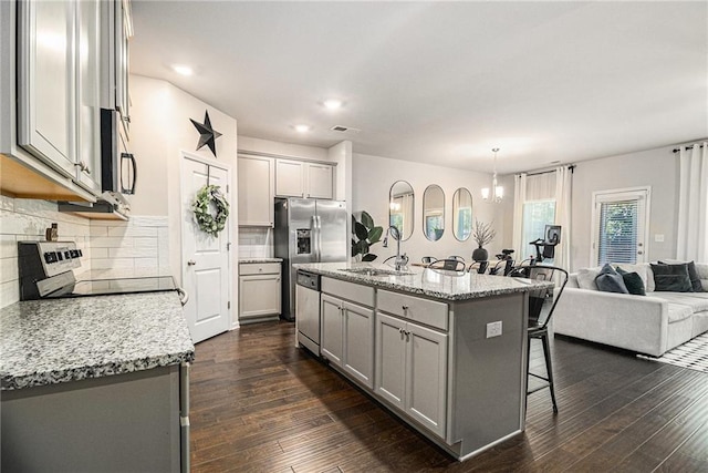 7086 Gladstone Cir, Lithonia, GA 30038 - kitchen featuring gray cabinets, appliances with stainless steel finishes, a breakfast bar area, tasteful backsplash, and dark wood-type flooring