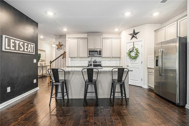 7086 Gladstone Cir, Lithonia, GA 30038 - kitchen with appliances with stainless steel finishes, dark wood-type flooring, a breakfast bar, backsplash, and recessed lighting