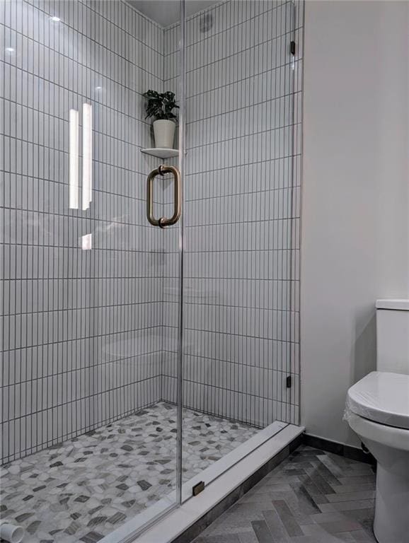 full bath featuring a stall shower, toilet, and baseboards