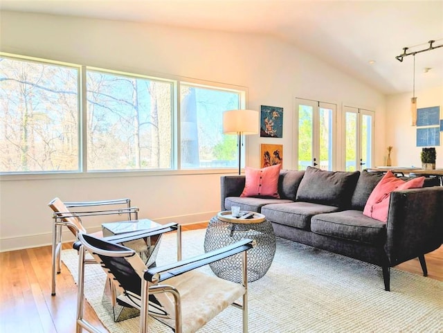 living room featuring lofted ceiling, light wood finished floors, and baseboards