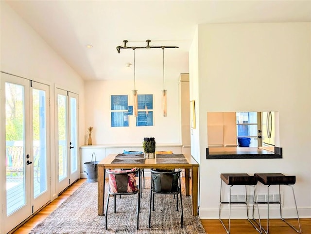 dining room with vaulted ceiling, light wood-type flooring, and baseboards