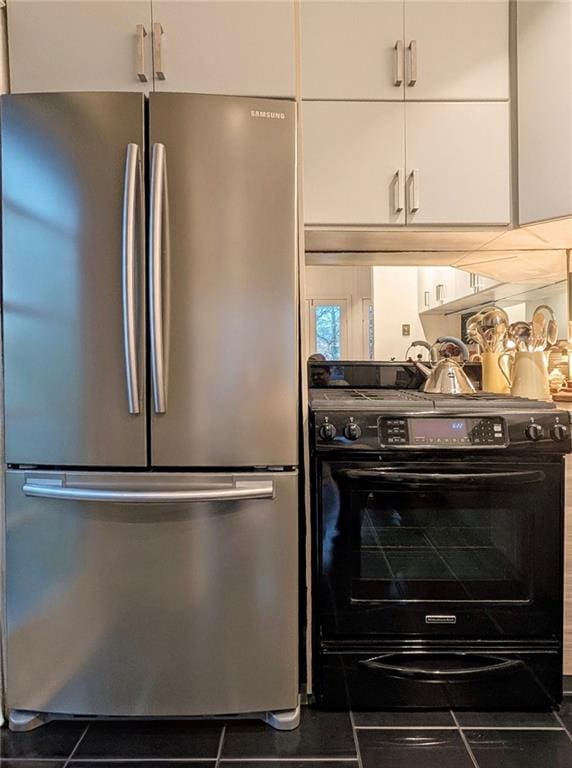 kitchen with electric range, white cabinets, and freestanding refrigerator