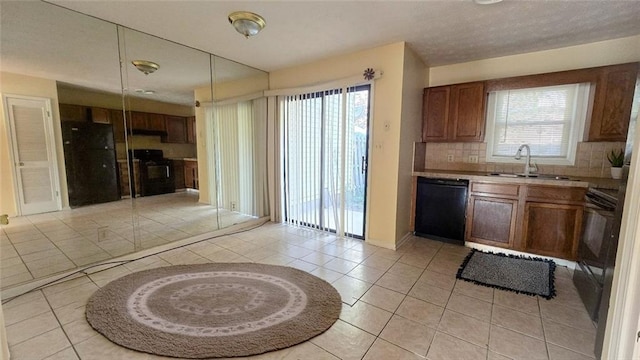 kitchen with light tile patterned floors, backsplash, black appliances, and a sink