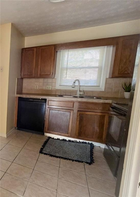 kitchen featuring dishwasher, decorative backsplash, light tile patterned flooring, and a sink