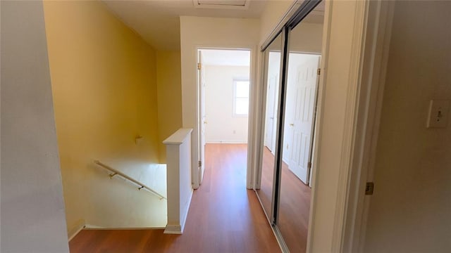 corridor featuring wood finished floors, an upstairs landing, and baseboards