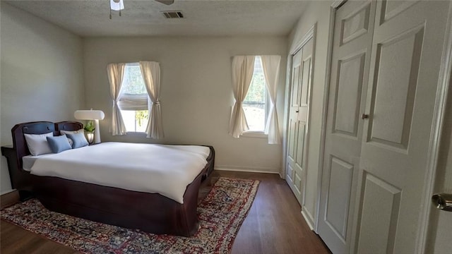 bedroom with dark wood-type flooring, baseboards, visible vents, and a textured ceiling