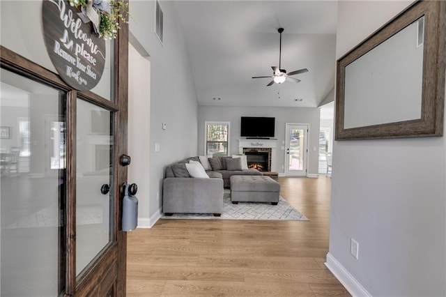 living room featuring lofted ceiling, ceiling fan, and light hardwood / wood-style flooring