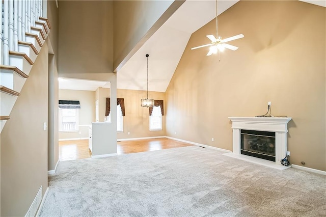 1008 Walnut Creek Dr, Woodstock, GA 30188 - unfurnished living room with carpet floors, a glass covered fireplace, baseboards, high vaulted ceiling, and ceiling fan with notable chandelier