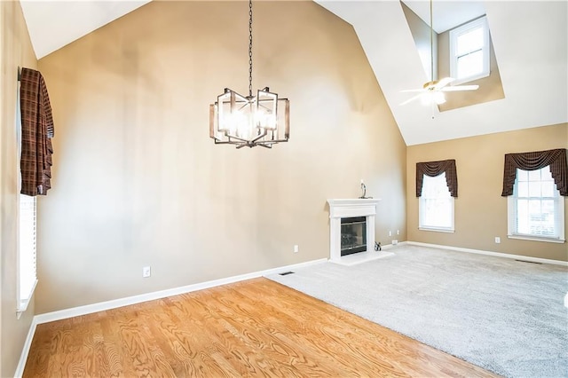 1008 Walnut Creek Dr, Woodstock, GA 30188 - unfurnished living room featuring wood finished floors, high vaulted ceiling, baseboards, ceiling fan with notable chandelier, and a glass covered fireplace
