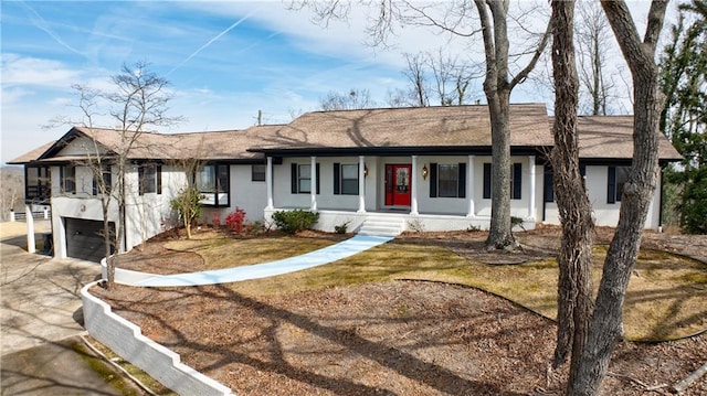 ranch-style house featuring a garage, covered porch, driveway, and stucco siding