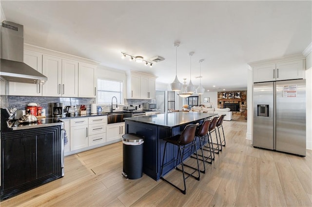 2316 Mountain Crest Pl, Gainesville, GA 30501 - kitchen with appliances with stainless steel finishes, wall chimney exhaust hood, dark countertops, light wood finished floors, and a kitchen island