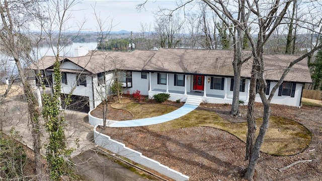 ranch-style house with covered porch, driveway, and stucco siding