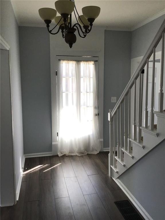 foyer featuring a notable chandelier, ornamental molding, and dark wood-type flooring