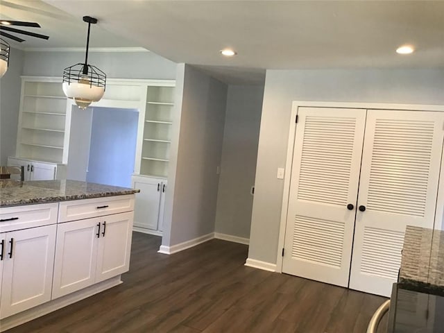 kitchen with white cabinetry, dark stone counters, ornamental molding, dark hardwood / wood-style floors, and pendant lighting