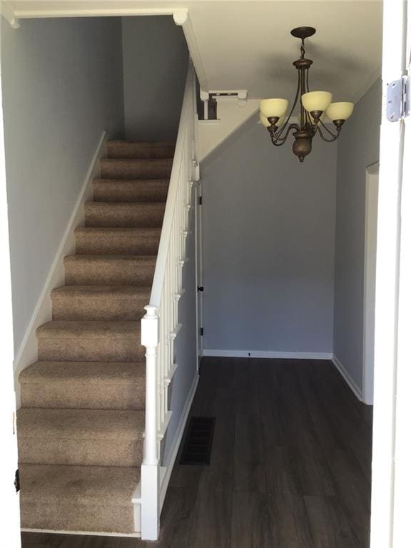 staircase featuring an inviting chandelier and wood-type flooring