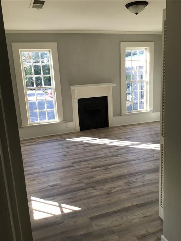 unfurnished living room featuring crown molding, hardwood / wood-style flooring, and plenty of natural light