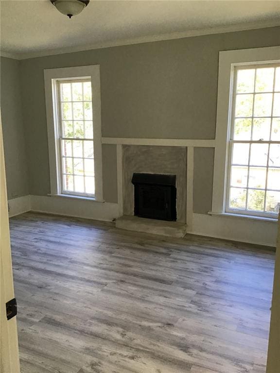 unfurnished living room with ornamental molding and wood-type flooring