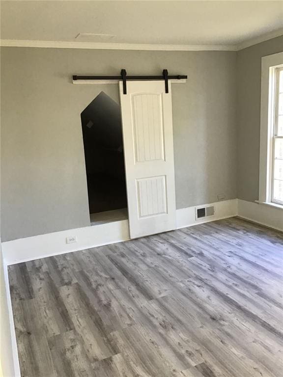 spare room with a barn door, wood-type flooring, and a wealth of natural light