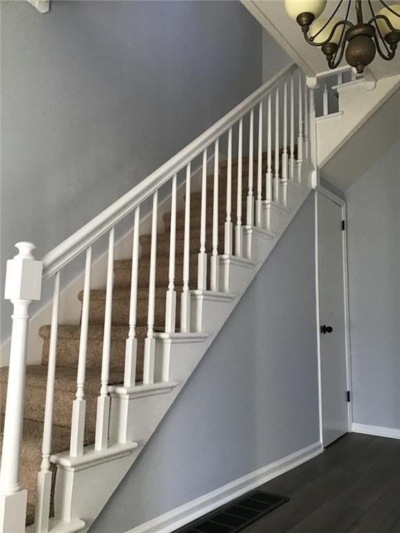 staircase featuring hardwood / wood-style flooring and a chandelier