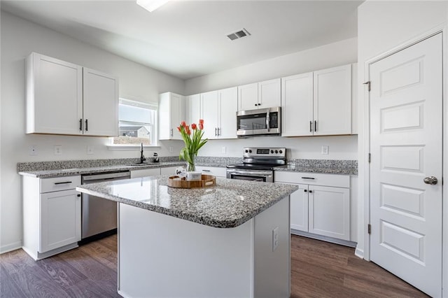 1628 Newport Dr, Bethlehem, GA 30620 - kitchen with stainless steel appliances, a sink, dark wood-type flooring, white cabinetry, and a center island