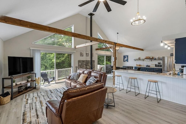 living room featuring ceiling fan with notable chandelier, high vaulted ceiling, and light wood-type flooring