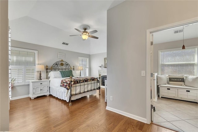 bedroom with lofted ceiling, visible vents, baseboards, and wood finished floors