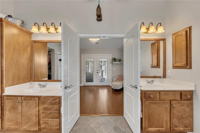 full bath with french doors, two vanities, a sink, and tile patterned flooring