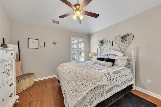 bedroom featuring baseboards, visible vents, vaulted ceiling, and wood finished floors