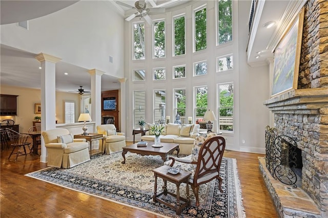 2630 Weddington Pl NE, Marietta, GA 30068 - living area with a fireplace, a ceiling fan, decorative columns, a high ceiling, and light wood-type flooring