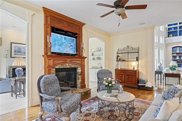 2630 Weddington Pl NE, Marietta, GA 30068 - living area featuring a stone fireplace, a ceiling fan, light wood finished floors, crown molding, and built in features