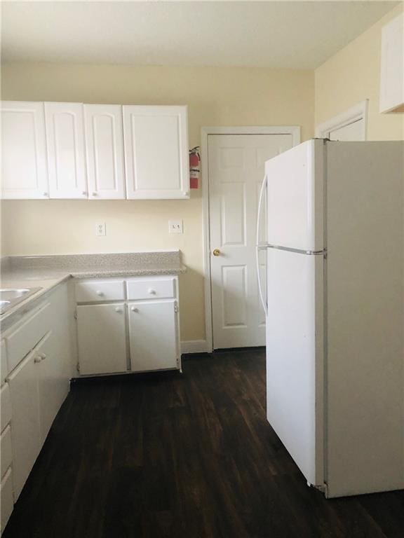 kitchen with white cabinets, dark hardwood / wood-style flooring, and white fridge