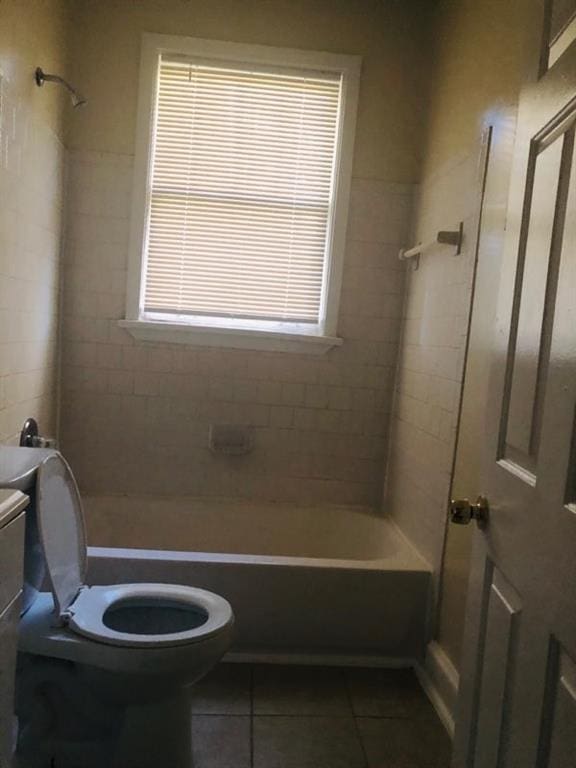 bathroom featuring tile patterned flooring, toilet, and tiled shower / bath