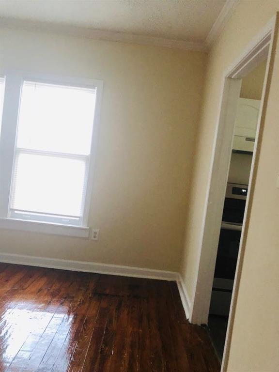 spare room featuring dark hardwood / wood-style flooring and crown molding